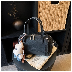 Detail of black faux leather Boston bag with plush bear charm and detachable strap