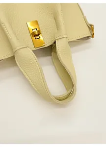 Détail d'un sac seau en cuir grainé avec poignée épaisse et fermoir doré rotatif