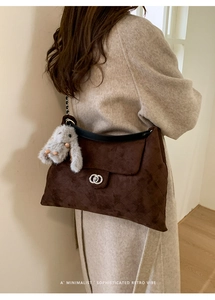 Detail der dunkelbraunen Wildleder-Tasche mit silberner Schnalle und Plüschhasen-Anhänger