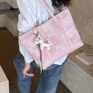 Detail view of pink plaid tote bag featuring a leather horse charm and shoulder straps