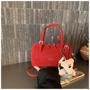 Detail of red matte leather Boston bag featuring silver hardware and a cute bear charm