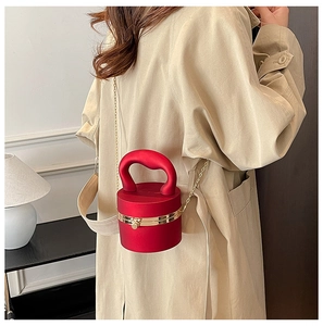 Detail of dark red cylindrical evening bag with gold clasp and elegant chain strap
