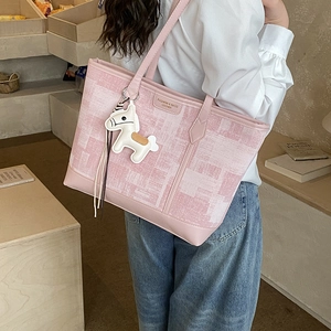 Pink plaid tote bag with leather label and horse charm shown on woman's shoulder