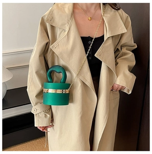 Close-up of emerald green mini bucket bag with gold hardware and curved handle