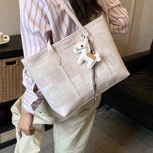Close-up of off-white tote bag with vertical stitching and a small horse charm detail