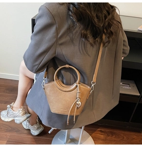 Detail of camel bucket bag with heart pendant, metal handle and adjustable strap