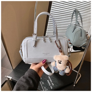 Detail of light blue leather boston bag with plush bear charm and silver double zippers