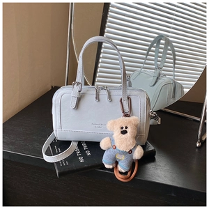 Detail of light blue leather boston bag with plush bear charm and detachable strap