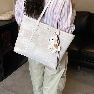 Detail of canvas tote bag with contrast leather strap and a decorative horse charm