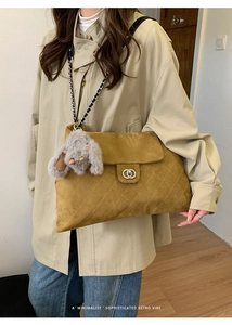 Makroaufnahme einer ingwergelben Wildleder-Tasche mit Rautensteppung und Ringschloss