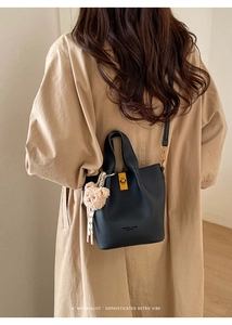Détail du sac seau en cuir noir avec fermoir doré et pendentif ours en peluche doux