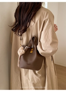 Détail du sac seau en cuir marron foncé avec fermoir doré et breloque ours en peluche