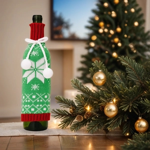 Close-up of green knitted wine bottle cover with red collar and white snowflake patterns