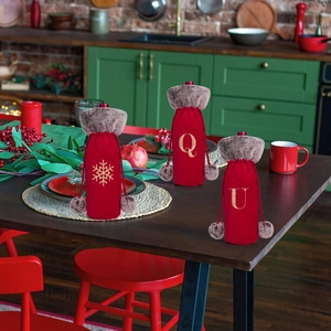 Detail of red plush wine bottle covers with faux fur collars and festive embroidery