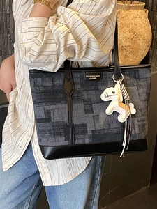 Navy blue denim tote bag with black leather trim and cute white horse charm accessory