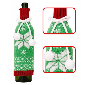 Close-up detail of knitted Christmas wine bottle cover with snowflakes and pompoms