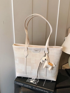 Cream canvas and leather tote bag featuring a metallic logo and small horse charm