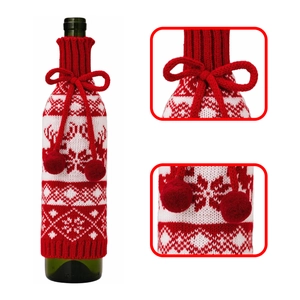 Detail of knitted Christmas wine bottle cover with snowflake patterns and red pom-poms