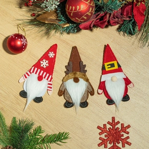 Trois porte-couverts gnomes de Noël sur bois avec des branches de pin et décorations
