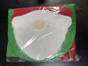Detail of Santa Claus toilet seat cover in green and red festive fabric packaging