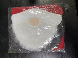 Detail of Santa Claus toilet seat cover in plastic packaging on black wooden background