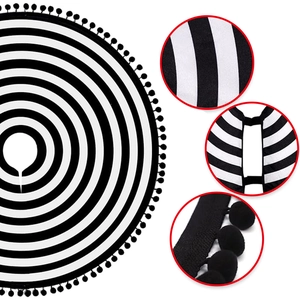 Close-up of black and white striped Christmas tree skirt with decorative pom-pom fringe