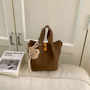 Détail du sac seau en cuir marron avec fermoir tournant doré et breloque en ours
