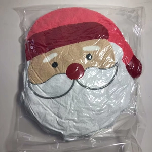 Detailed close-up of Santa Claus plush pillow inside protective plastic packaging