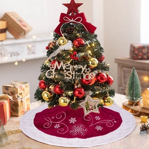 Close-up of red velvet Christmas tree skirt with white plush trim and silver snowflakes