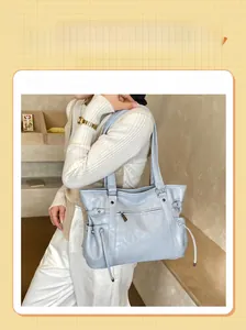 Close-up of light blue leather tote bag showing side drawstring detail and soft texture