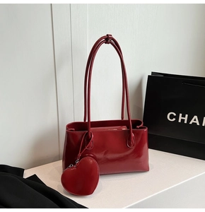 Detail of burgundy glossy faux leather tote bag with heart charm and slim shoulder straps