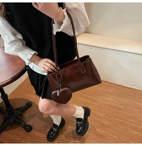 Close-up of vintage coffee brown oil wax leather tote bag with heart-shaped coin purse charm