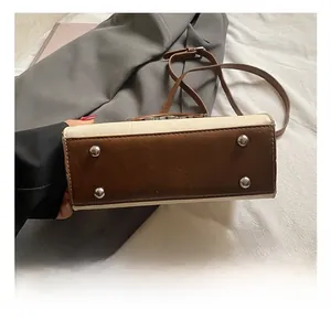 Detail of the handbag base with four silver metal protective feet and brown leather trim