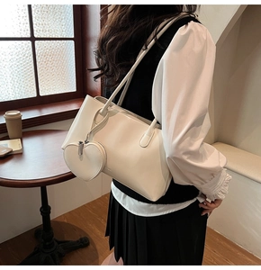 Detail of a chic cream shoulder bag with a stylish heart-shaped charm accessory