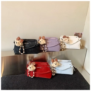Group view of five textured matte handbags with decorative plush bear charms and beads