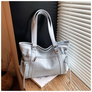 Detail of light blue leather tote bag showing fine texture and front zipper pocket