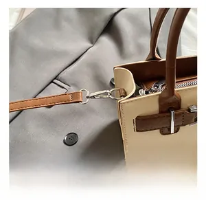 Detail of silver metal buckle and detachable shoulder strap on beige leather handbag