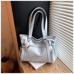 Close-up of light blue PU leather tote bag with zip pocket on a wooden desk