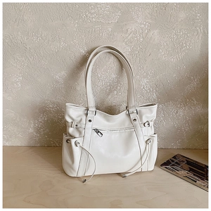 Close-up of white tote bag showing soft leather texture and side drawstring details