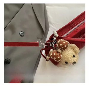 Detail of red bucket bag with metallic silver hooks and a cute plush bear charm