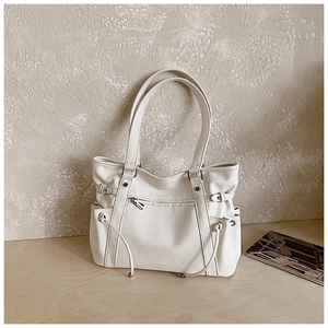 Detail of off-white tote bag showing side storage pockets and decorative drawstrings