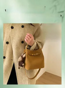 Detail of yellow bucket bag with matte suede texture and cute monkey plush charm