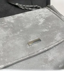Détail du sac argenté métallisé avec chaîne en métal et plaque logo de marque gravée