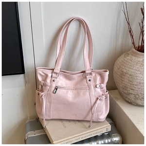 Detail of light pink tote bag with front zipper and side drawstring pockets on a suitcase