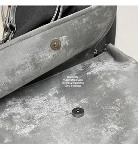 Détail du fermoir magnétique caché et de la chaîne argentée sur le sac gris texturé