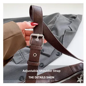 Detail view of adjustable shoulder strap with silver buckle and star pendant on brown bag