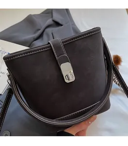Close-up of a dark brown leather bucket bag featuring a silver twist lock and white stitching