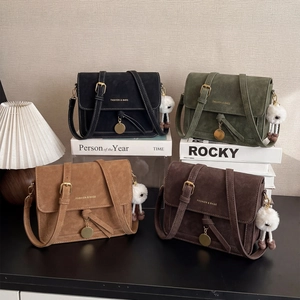 Detail of four chic crossbody bags in black, green, brown, and coffee with fur ball charms