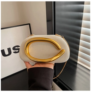 Detail of cream woven fabric clutch featuring a large irregular gold metal ring and chain