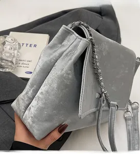 Gros plan sur le sac à bandoulière gris mat avec chaîne argentée et rabat élégant